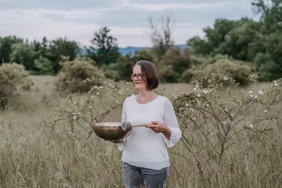 Christina Plate mit Klangschale in der Natur Wenn Abschalten schwerfällt: Regeneration wird wichtiger