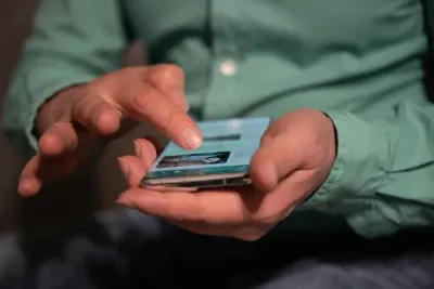 Mann aktiviert den Flugmodus am Smartphone, auf der Rückseite ist ein unsichtbarer Schungit-Stein. Flugmodus & Schungit - Was haben sie gemeinsam?
