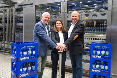 Am Startknopf: V. Harbecke (Geschäftsführer), S. Huneke (L. Marketing), S. Wortmann (L. Technik) Carolinen: Marktführer in OWL drückt Startknopf für neue Flaschen und Kästen